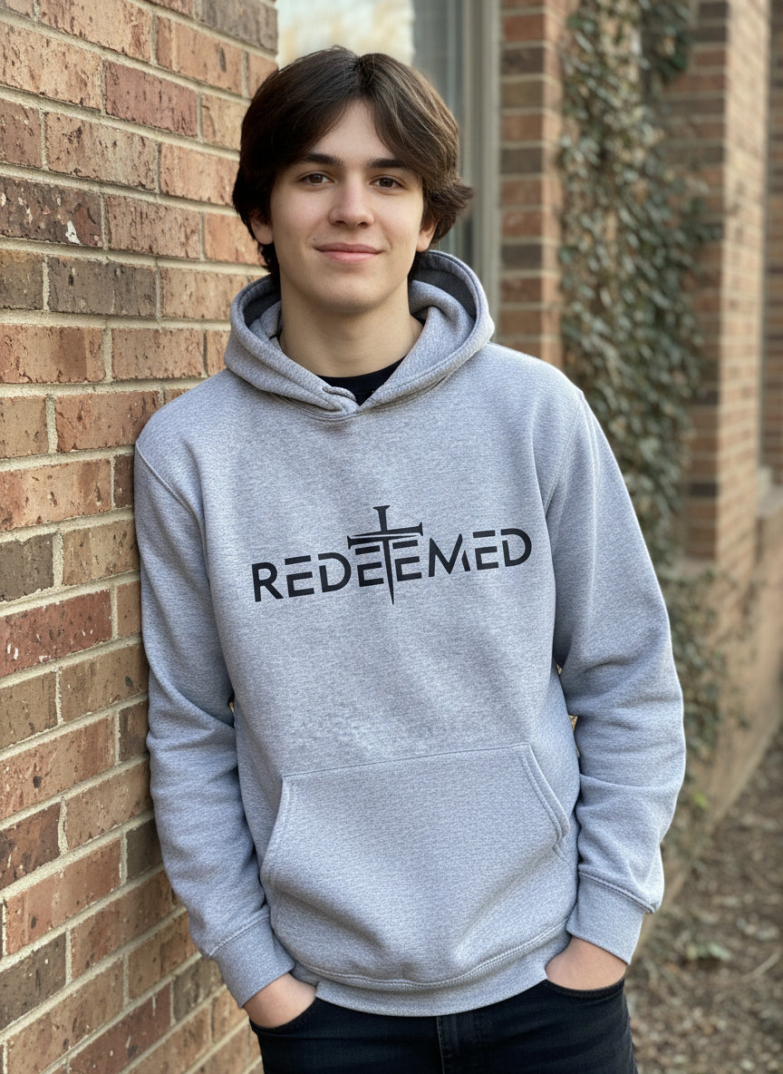Gray sweatshirt with 'REDEEMED' text and cross design on a plain background