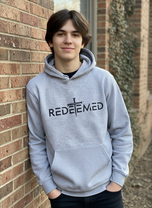 Gray sweatshirt with 'REDEEMED' text and cross design on a plain background